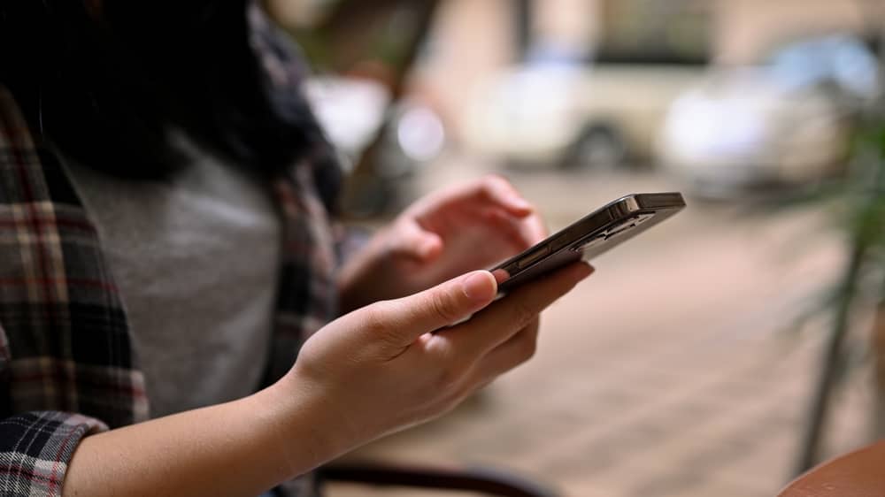 mains d'une femme envoyant un message à Jean-Pierre Foucault avec son smartphone