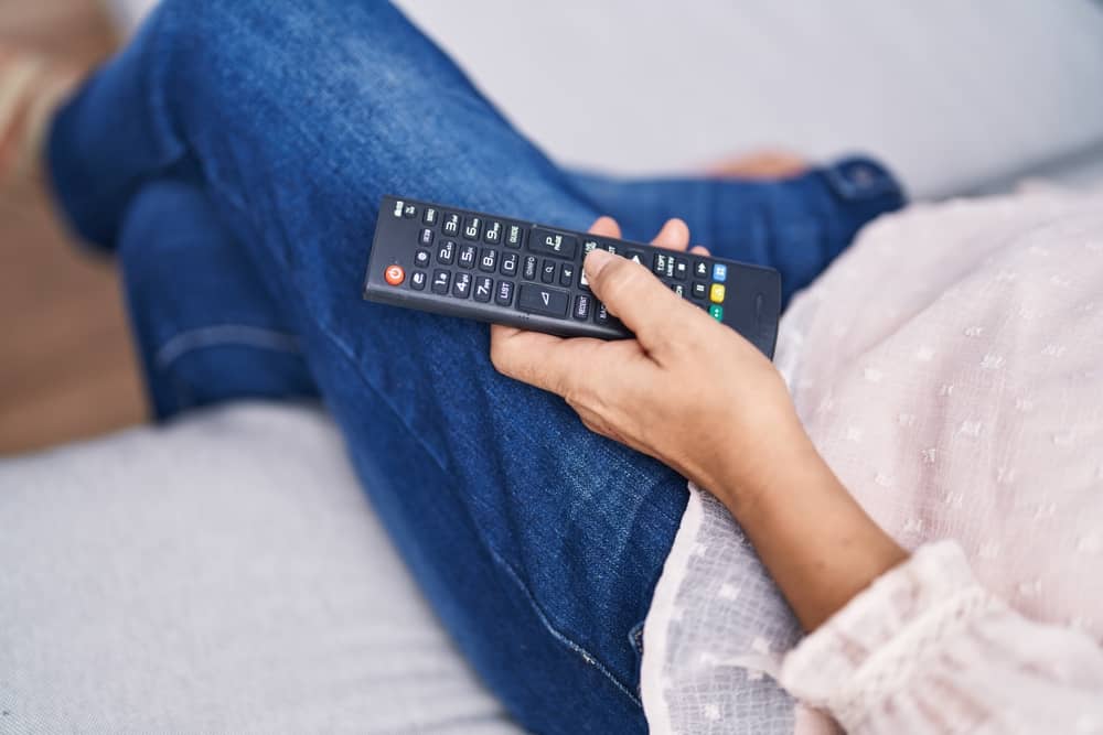 femme tenant une télécommande pour regarder Angers Télé