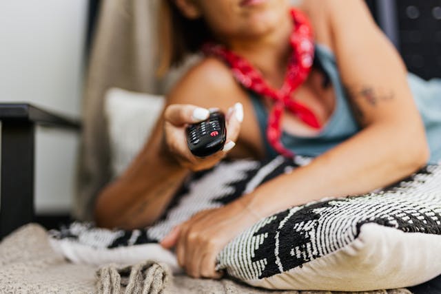 femme regardant la chaine ATV avec une télécommande à la main