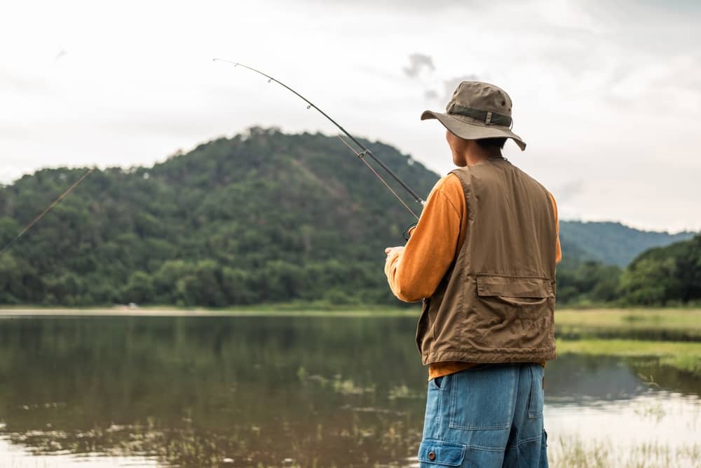 homme de dos en train de pêcher dans un lac