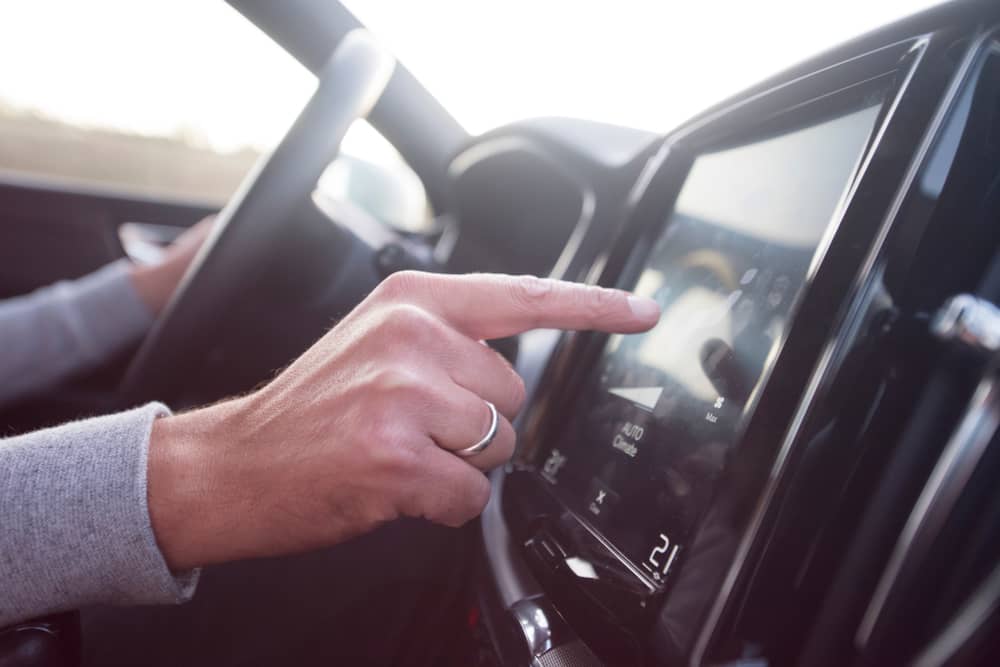 main d'un homme allumant Deezer dans sa voiture