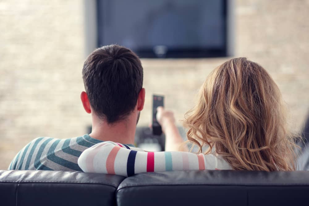 couple sur un canapé allumant la télévision pour regarder Demain TV