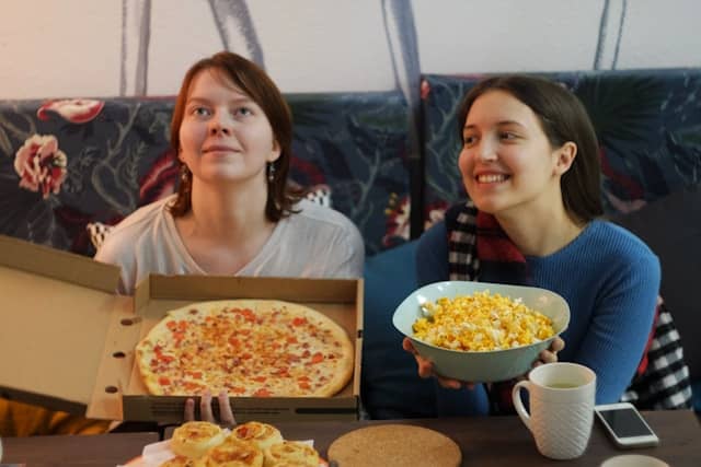 deux jeunes femmes en train de regarder Disney Channel avec des popcorns et une pizza