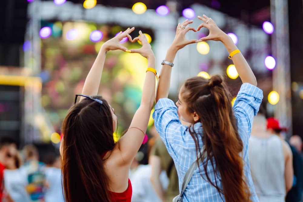 deux femmes faisant un coeur avec leurs mains devant une scène des Francofolies