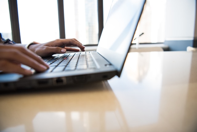 mains d'une personne envoyant un message à Maya Lauqué sur son ordinateur portable