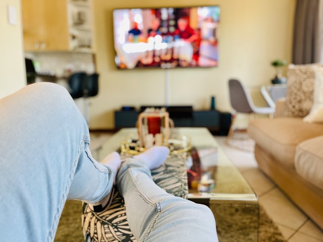 personne regardant la télé via Molotov TV avec les jambes sur la table basse