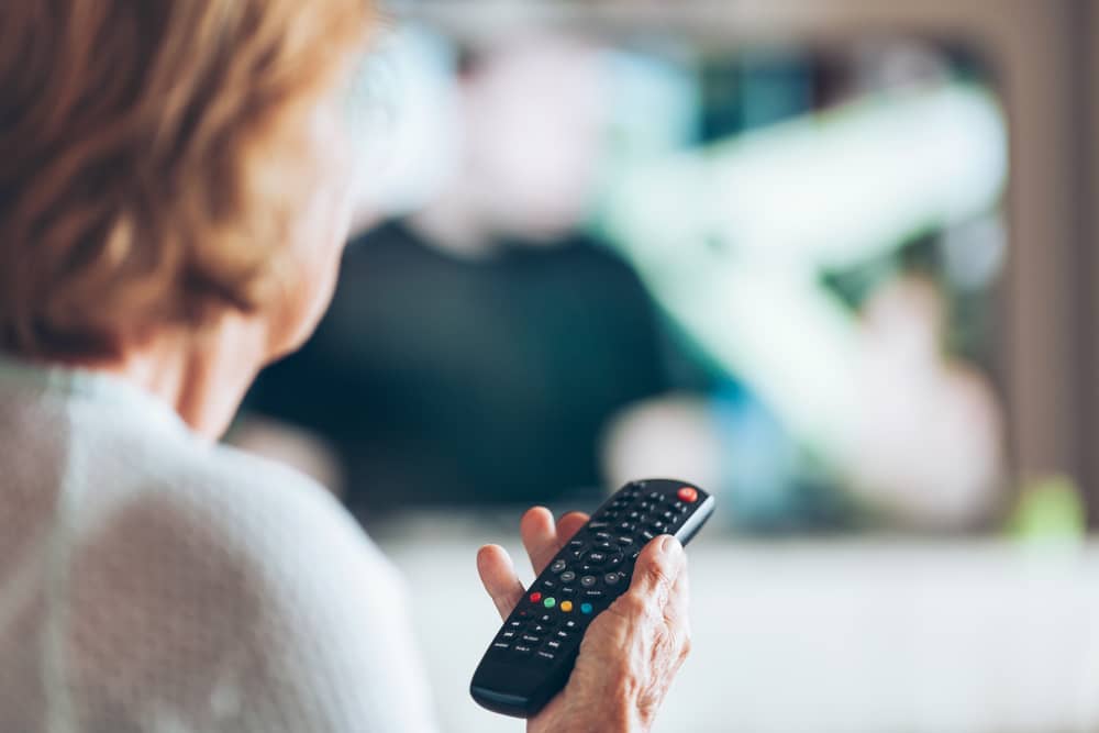 femme regardant myCANAL sur sa télévision, avec une télécommande à la main