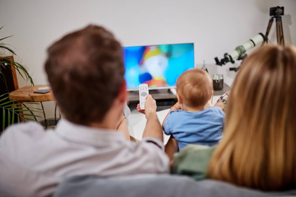 un couple et son bébé regardent un dessin-animé sur une chaîne OCS