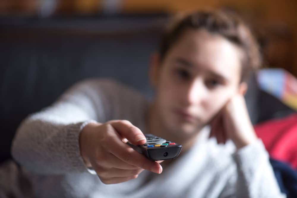 jeune fille avec une télécommande dans la main pour regarder RMC Sport