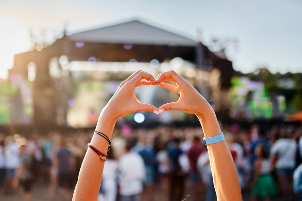 personne formant un coeur avec ses mains devant une scène des Solidays