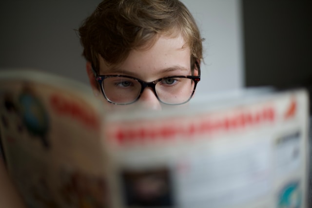 adolescent avec des lunettes en train de lire le magazine Télé Star