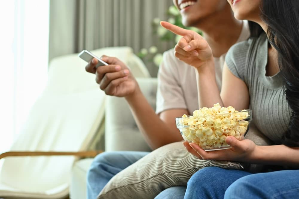 couple regardant TF1 Séries Films en mangeant des popcorns