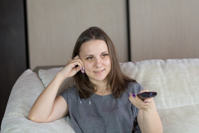 femme regardant la chaîne Top Santé TV avec une télécommande à la main