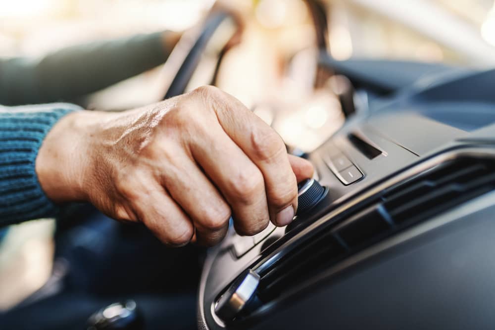 main d'un homme montant le son de la radio Toulouse FM dans sa voiture