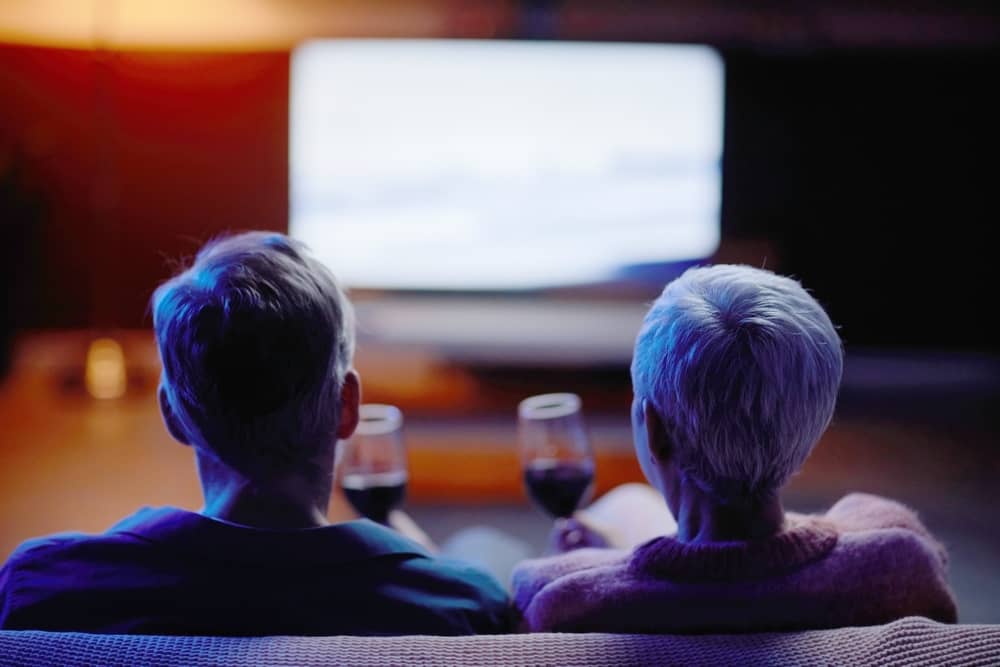 vue de dos d'un couple en train de regarder Ushuaia TV assis sur un canapé