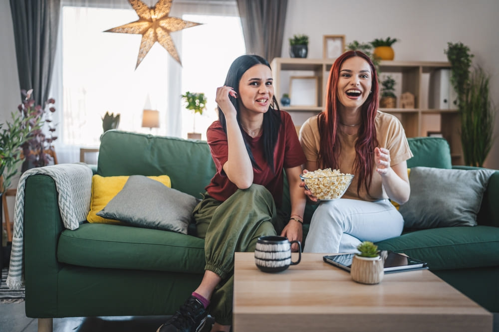 deux jeunes femmes regardant la chaîne Wéo Picardie avec des popcorns