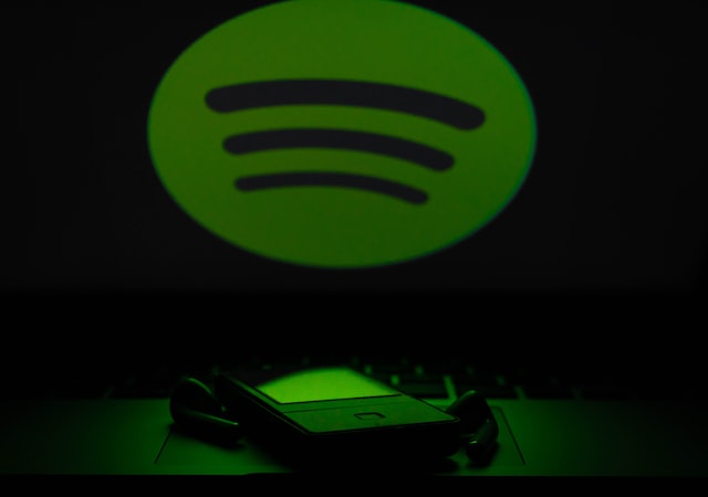 logo spotify au-dessus d'un smartphone et d'écouteurs