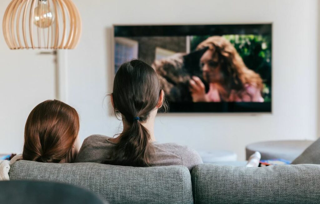 Mère et fille dans un canapé regardant Warner Bros à la télévision