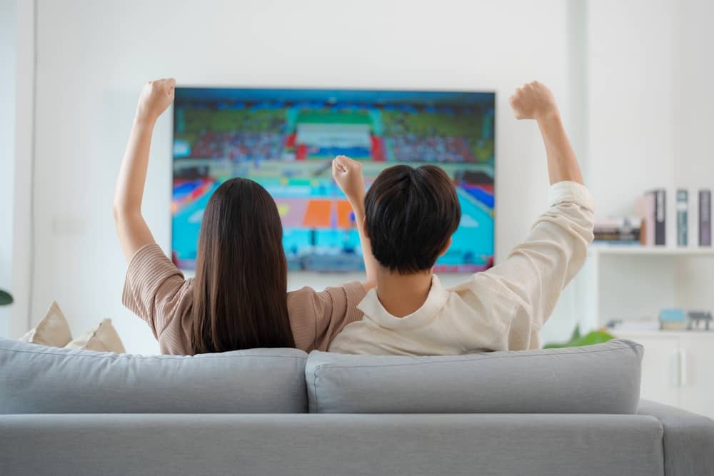 couple sur un canapé regardant un événement sportif sur France 2 depuis l'étranger