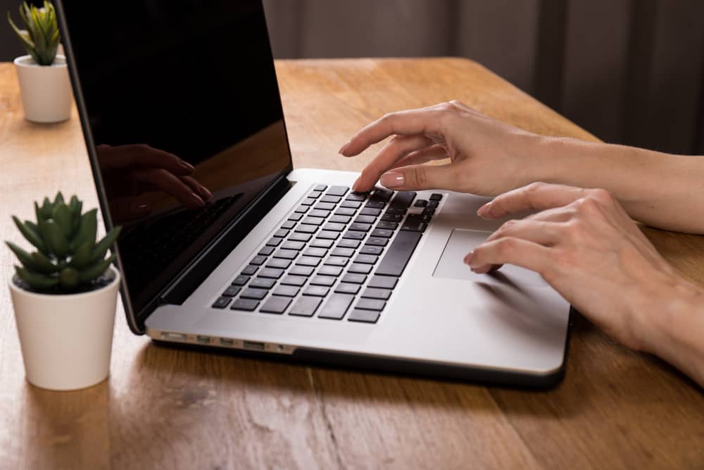 mains d'un homme faisant un signalement à l'ARCOM depuis son ordinateur portable